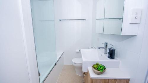 a white bathroom with a toilet and a sink at SUNSET@CORLETTE in Corlette