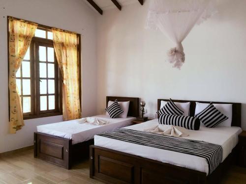 a bedroom with two beds and a window at Isanka Lion Lodge in Sigiriya