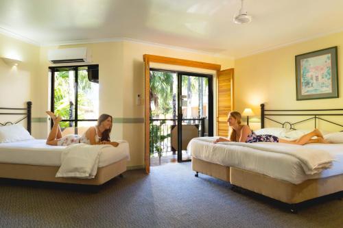 ケアンズにあるパーム ロワイヤル ケアンズのホテルの部屋のベッドに横たわっている女性2名