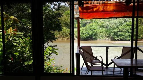 a view of a river from a window with a table and chairs at Boca Tapada Lodge in Boca Tapada