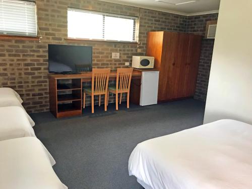 a room with two beds and a desk with a television at Lake Albert Motel in Meningie