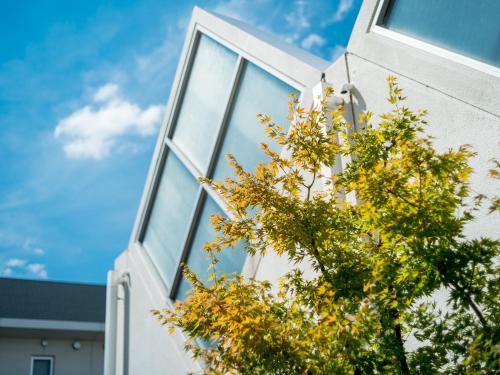 a building with windows and a tree in front of it at Super Hotel Nara Yamato Koriyama in Yamatokoriyama