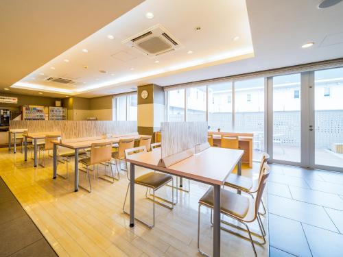 a dining room with tables and chairs and windows at Super Hotel Nara Yamato Koriyama in Yamatokoriyama