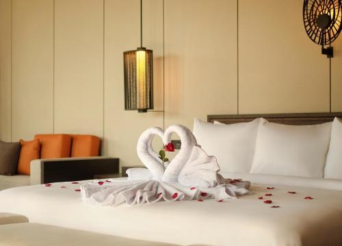 two swans dressed in white are sitting on a bed at Radisson Blu Bali Uluwatu in Uluwatu
