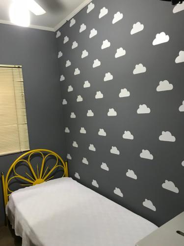 a bedroom with a gray wall with clouds stencils at Pousada Santa Lolla in São Carlos