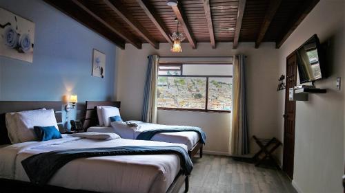 a hotel room with two beds and a window at Hotel Colonial San Agustin in Quito