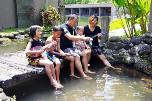 
three women and two men are sitting on a riverbank at The Westlake Hotel & Resort Yogyakarta in Yogyakarta
