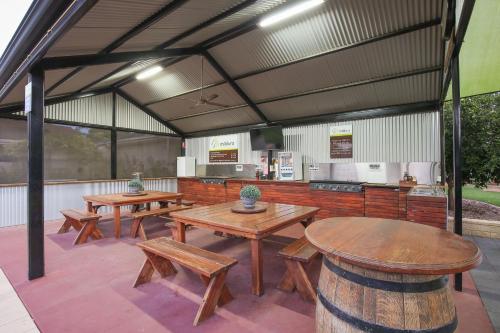 a patio with wooden tables and benches and a kitchen at Mildura Holiday Villas in Mildura