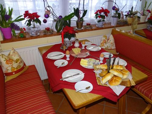 a table with a red table cloth with food on it at Pension Bayrhammer in Faistenau