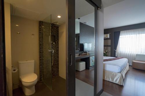 a bathroom with a shower and a toilet and a bed at Kiss Gardenhome Chic Hotel in Hat Yai
