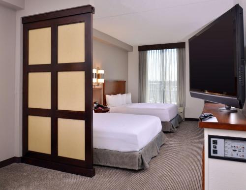 a hotel room with two beds and a flat screen tv at Hyatt Place Garden City in Garden City