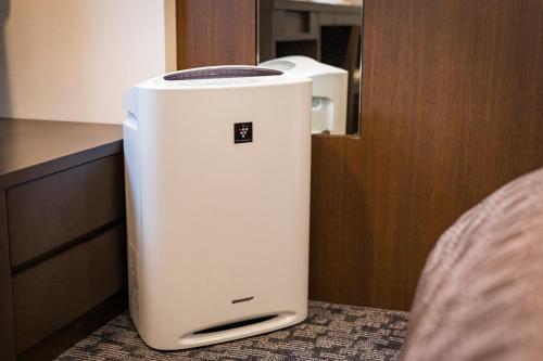 a white refrigerator sitting on the floor next to a bed at Nishitetsu Inn Kokura in Kitakyushu