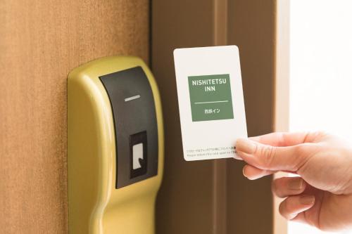 a person holding a smart phone in a hotel room at Nishitetsu Inn Kokura in Kitakyushu