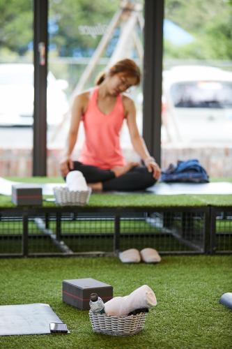 a woman sitting on a table with her feet on the ground at Playce Camp Jeju in Seogwipo