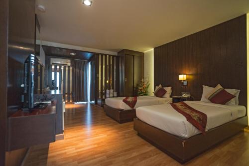 a hotel room with two beds and a television at Kiss Gardenhome Chic Hotel in Hat Yai