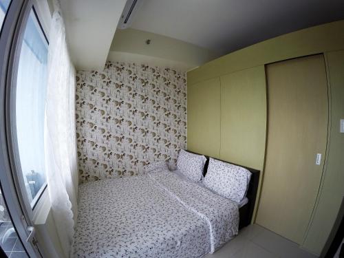 a small bedroom with a bed and a window at Wind Residence Condo - Tagaytay by jaderooms in Tagaytay
