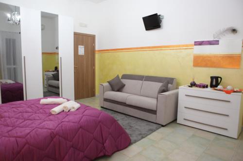 a bedroom with a purple bed and a couch at Agriturismo Il Pavone in Torre Lapillo