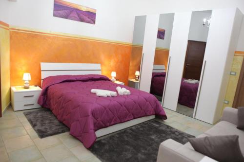 Un dormitorio con una cama púrpura con dos animales de peluche. en Agriturismo Il Pavone en Torre Lapillo