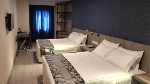 two beds in a hotel room with a window at Diamond Inn in Kota Kinabalu
