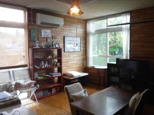 a living room with a couch and a tv and a table at Okinawa Hostel Yanbaru Fukuro in Nago