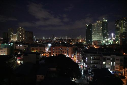 a city lit up at night with tall buildings at Z Hostel in Manila