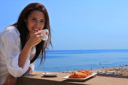 a woman sitting at a table taking a picture of food at Hotel Liberty Beach - Parking & Beach in Riccione