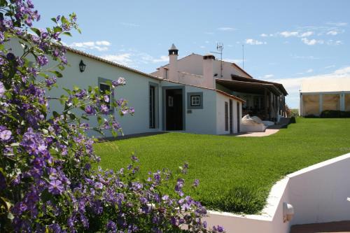 a house with a yard with purple flowers at Monte Da Morena Agro-Turismo in Serpa