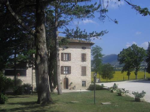 un grande edificio in mattoni con un albero di fronte di Villa Pascolo a Costacciaro