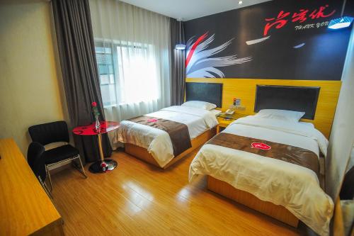 長沙市にあるThank Inn Chain Hotel Hunan Changsha Furong District Railway Stationのベッド2台が備わる客室で、壁に看板が付いています。
