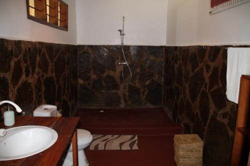 a bathroom with a sink and a toilet and a tub at Camp Bastian Mikumi in Mikumi