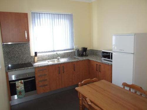 a kitchen with a table and a white refrigerator at Paraiso das Flores in Estreito da Calheta