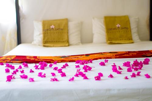 a bunch of pink flowers on a bed at Walampuri Cabana & Restaurant in Tangalle