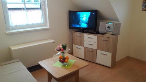 - un salon avec une télévision et une table avec des fruits dans l'établissement Ferienwohnung 15 in Koserow, à Ostseebad Koserow