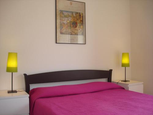 a bedroom with a pink bed and two lamps at Casa Le Querce in Ogliastro Cilento