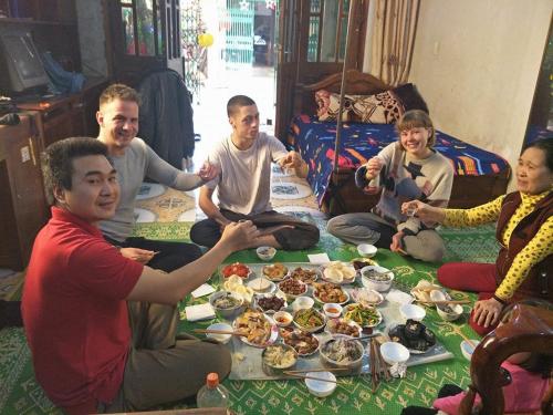 a group of people sitting around a table eating food at Ngan Ha Homestay in Ha Giang