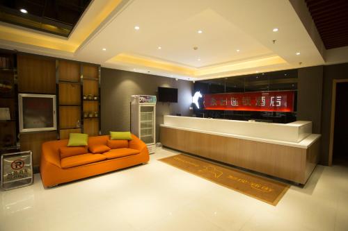 PingshanにあるJUNYI Hotel Hebei Shijiazhuang Pingshan Town Wanshou Roadのリビングルーム(オレンジ色のソファ、テレビ付)