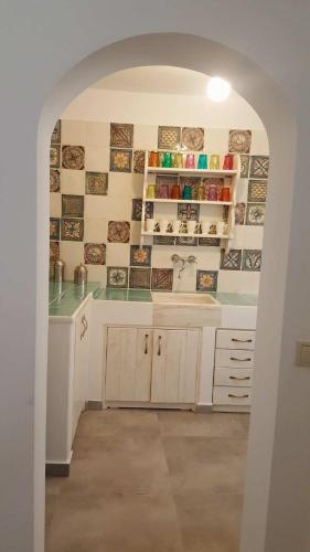 a kitchen with white cabinets and a white sink at Amalthia House in Arkasa