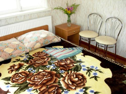 a bedroom with a bed with a flower blanket and two chairs at Albatross in Kaunata