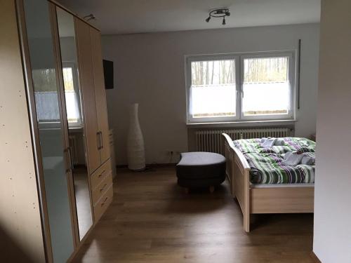 a bedroom with a bed and a dresser and two windows at Frankenstube in Eichelsdorf