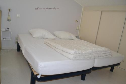 Au Pas Du Chateau في جونزاك: سرير بشرشف ووسائد بيضاء في الغرفة