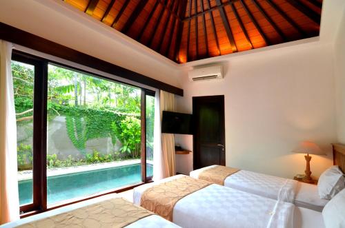 a bedroom with two beds and a large window at New Pondok Sara Villas - CHSE Certified in Seminyak