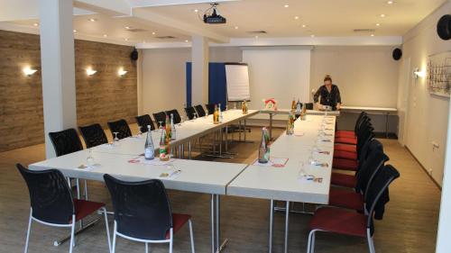 a woman standing in front of a long table in a room at ACHAT Hotel Monschau in Monschau