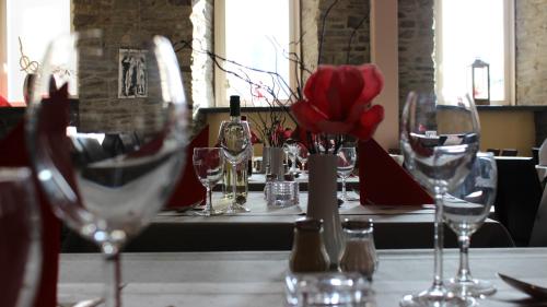 a table with wine glasses and red flowers on it at ACHAT Hotel Monschau in Monschau