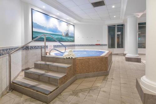 a jacuzzi tub in a lobby with a large painting at Leonardo Royal Southampton Grand Harbour in Southampton