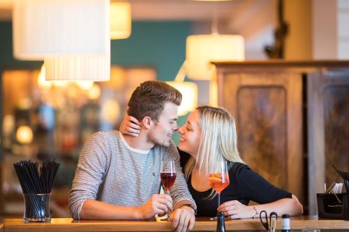 a man and woman sitting at a table with a glass of wine at Hotel Weingarten in Appiano sulla Strada del Vino