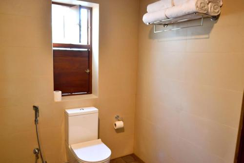 a bathroom with a toilet and a window and towels at Kethaka Aga in Tissamaharama