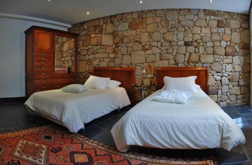 2 camas en una habitación con una pared de piedra en Casa Museu, en Vouzela