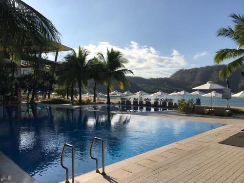 a large swimming pool with palm trees and umbrellas at Creys Condo 2 at Pico de Loro Cove in Nasugbu