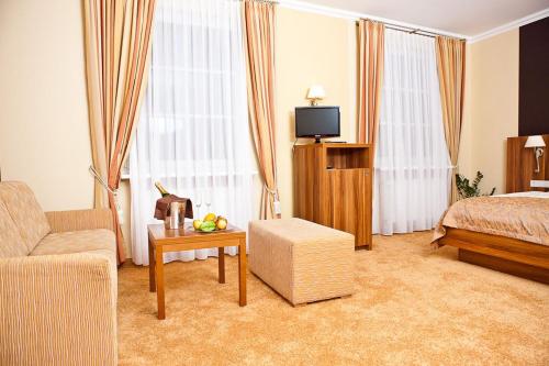 um quarto de hotel com uma cama, um sofá e uma televisão em Dagstuhler Hof em Wadern