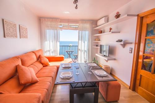 ein Wohnzimmer mit einem Sofa und einem Tisch in der Unterkunft Piso primera línea de playa in Málaga